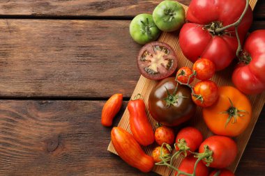 Ahşap masada farklı olgun domatesler, üst manzara. Metin için boşluk
