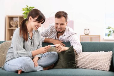 Evdeki koltukta hamilelik testi olan mutlu genç çift.