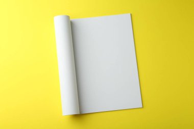Sarı arka planda boş sayfası olan açık dergi, üst görünüm. Tasarım için model