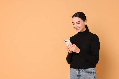 Bej arka planda akıllı telefonu olan gülümseyen bir kadın. Metin için boşluk