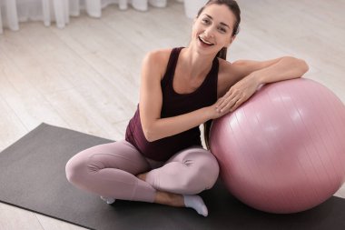 Egzersiz paspasında spor topuyla güzel hamile bir kadın.