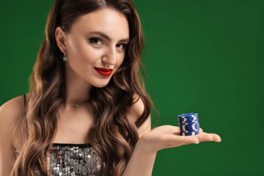 Yeşil arka planda poker fişleri olan çekici bir kadın.