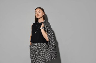 Gri arka planda şık takım elbiseli güzel kadın, mesaj için yer var.