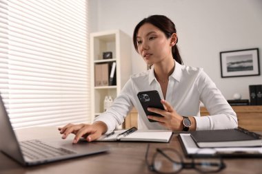 Ofiste çalışan akıllı telefonlu güzel bir iş kadını. Düşük açılı.