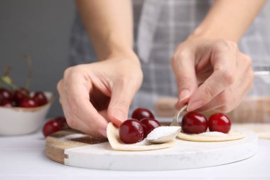 Beyaz masada kirazlı börek yapan kadın, yakın plan.