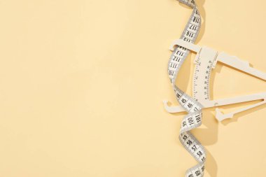 Plastik vücut yağ kalibreli ve bej arka planda mezura, üst görünüm. Metin için boşluk