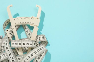 Plastik vücut yağ kalibreli ve açık mavi arka planda mezura, üst görünüm. Metin için boşluk