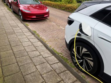 Şehir caddesinde modern elektrikli araba şarj oluyor.