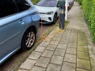 Şehir caddesinde modern elektrikli araba şarj oluyor.