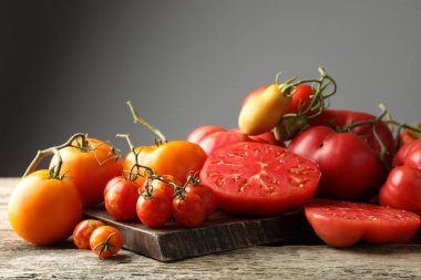 Many different ripe tomatoes on wooden table