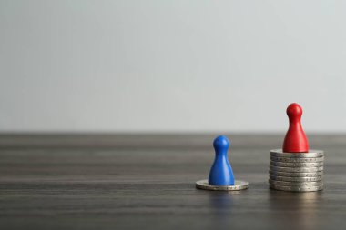 Finansal eşitsizlik. Ahşap masada insan figürleri ve madeni paralar. Metin için boşluk