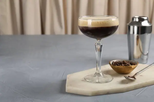 stock image Fresh coffee cocktail in glass, beans and bartender equipment on grey table, space for text