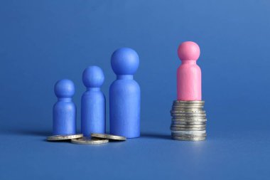 Finansal eşitsizlik. Mavi arka planda bozuk para miktarı eşit olmayan erkek ve kadın figürleri