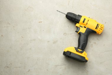 Açık gri masada modern kablosuz elektrikli matkap, üst manzara. Metin için boşluk