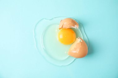 Kırık çiğ yumurta ve açık mavi arka plan, üst görünüm.