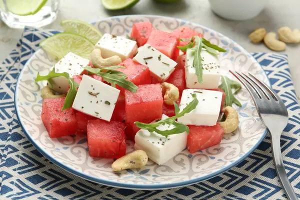 Feta peynirli nefis karpuz salatası, fındık ve baharatlar ışıklı masada servis edilir.