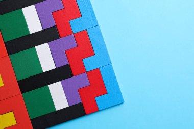 Açık mavi zemin üzerinde renkli ahşap yapboz parçaları, üst manzara. Metin için boşluk