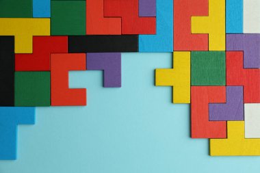 Açık mavi zemin üzerinde renkli ahşap yapboz parçaları, üst manzara. Metin için boşluk