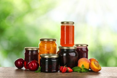 Reçelli kavanozlar ve ahşap masada korunmuş meyveler.