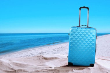 Denize yakın kumsalda açık mavi bir bavul. Metin için boşluk