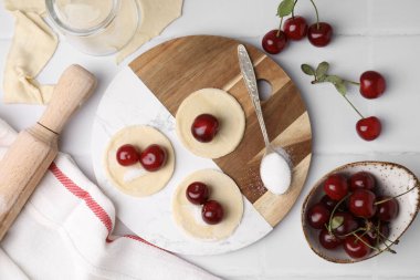 Kirazlı hamur tatlısı yapma süreci (varenyky). Çiğ hamur ve malzemeler beyaz döşeme üzerinde, düz yatıyordu
