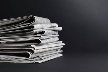 Siyah arka planda farklı dillerde gazete yığını. Metin için boşluk