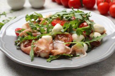 Gri desenli masada roka ile lezzetli salata, yakın plan.