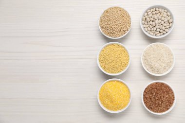 Tahıl gevreklerinin ve baklagillerin farklı türleri beyaz ahşap masada, düz yerde. Metin için boşluk