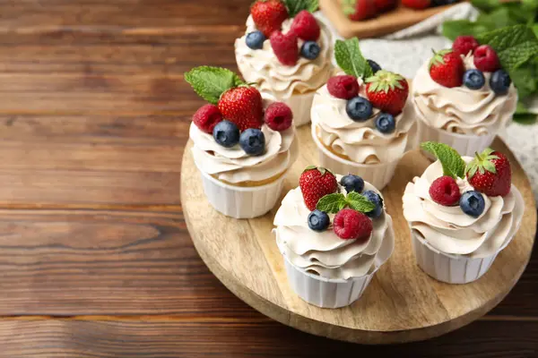 stock image Tasty cupcakes with different berries and mint on wooden table, closeup. Space for text