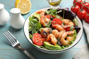 Lezzetli karides salatası ve açık mavi ahşap masa malzemeleri, yakın plan.