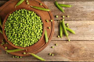 Taze bezelyeler kasede ve kabuklar ahşap masada, düz yerde. Metin için boşluk