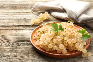 Taze üzümlü üzümler ve yeşil yapraklar ahşap masada, yakın plan.