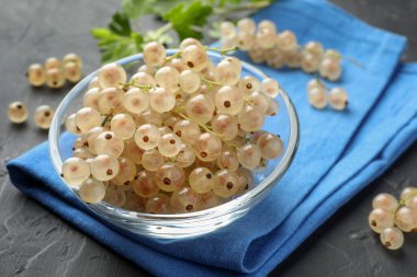 Kasede taze kuşüzümü ve gri desenli masada yeşil yapraklar, yakın plan.