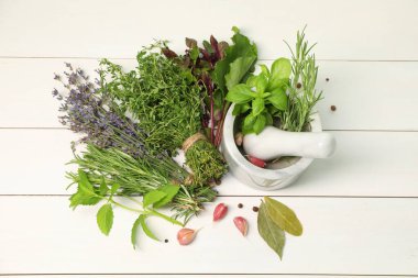 Farklı aromatik otlar, sarımsak, harç ve tokmak beyaz ahşap masa, üst görünüm