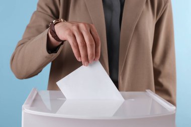 Kadın oyunu açık mavi arka plana karşı sandığa koyuyor, yakın plan.