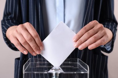 Kadın oyunu gri arka planda sandığa koyuyor, yakın plan.