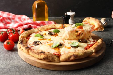Gri masada lezzetli vejetaryen pizzasından bir parça alıyorum, yakın plan.