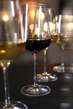 Siyah masada, bulanık ışıklara karşı farklı tatlı şaraplar, yakın plan.