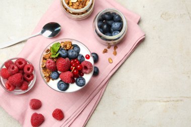 Taze böğürtlenli yoğurt, granola, bardakta nane ve gri desenli masada kaşık, düz yatak. Metin için boşluk