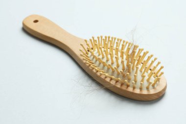 Gri arka planda saçı dökülmüş bir fırça. Alopecia sorunu
