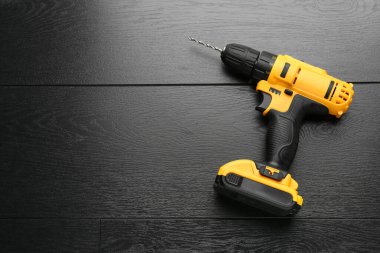 Kablosuz elektrikli matkap, siyah ahşap masa, üst manzara. Metin için boşluk