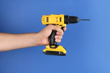 Mavi arka planda kablosuz matkabı olan adam, yakın plan.