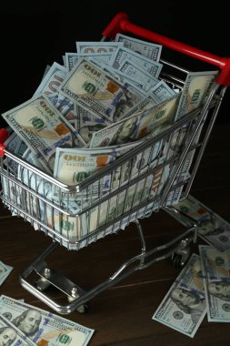 Birçok dolarlık banknotlar ahşap masada alışveriş arabasında, yakın plan.
