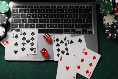 Laptop, poker fişleri, zarlar ve yeşil masada oyun kartları. Çevrimiçi oyun