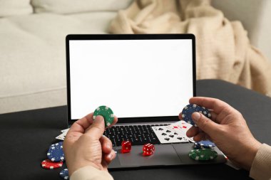 Siyah masada dizüstü bilgisayarlı bir adam poker oynuyor, yakın plan. Çevrimiçi oyun