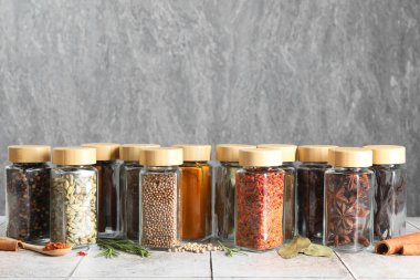 Işık döşeli masada cam kavanozlardaki farklı baharatlar, metin için yer