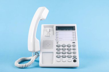Açık mavi arkaplanda cep telefonu olan beyaz telefon