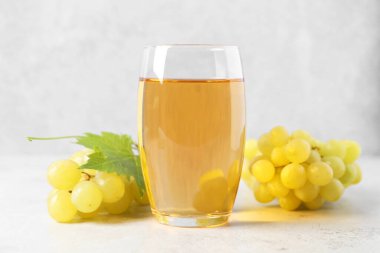 Bardakta üzüm suyu, açık dokulu masada yaprak ve böğürtlen, yakın plan.