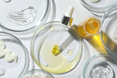 Beyaz arka planda farklı kozmetik ürünlere sahip petri kapları, düz yatıyordu