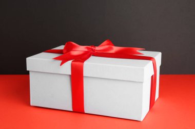 Arkaplanda kırmızı fiyonk olan hediye kutusu